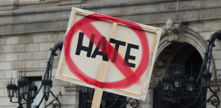 A sign with the word hate crossed out in red