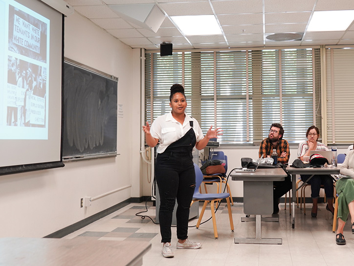 A woman teaching a class in a classroom from the MaSS department